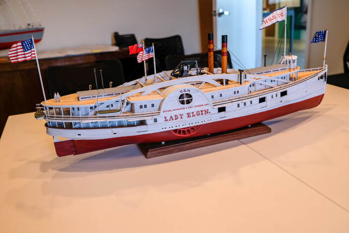 Model of the Lady Elgin, photographed on a table with other ship models in the background.