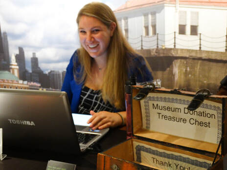 CMM receptionist smiles at the camera, next to a donation box on the museums front desk