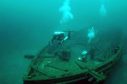 The wreck of the rouse simmons, underwater. A diver examines the front of the wreck.